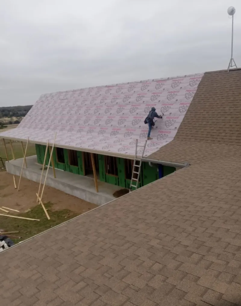 Worker preparing underlayment for a metal roof installation in Coal City